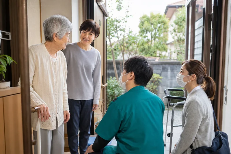 自宅の玄関で利用者と家族を地域の支援者が訪ねる様子