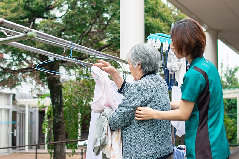 洗濯物を干す動作を職員と一緒に確認する利用者